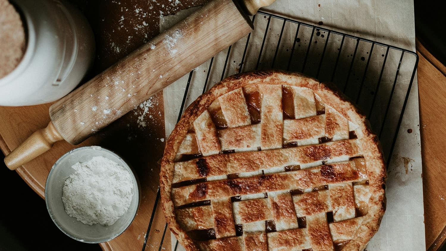 a pie rests on a counter by a rolling pin